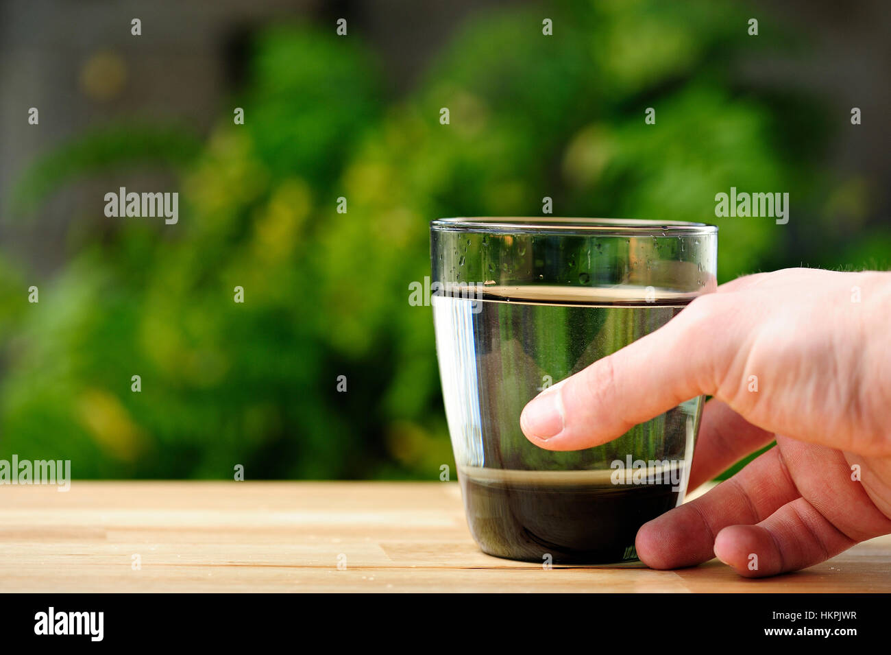 close up of hand with glass of water on table green park Stock Photo