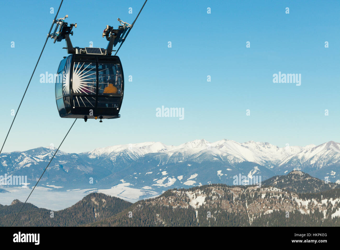 Cable car cabin going up above the clouds to the top of a mountain with ...