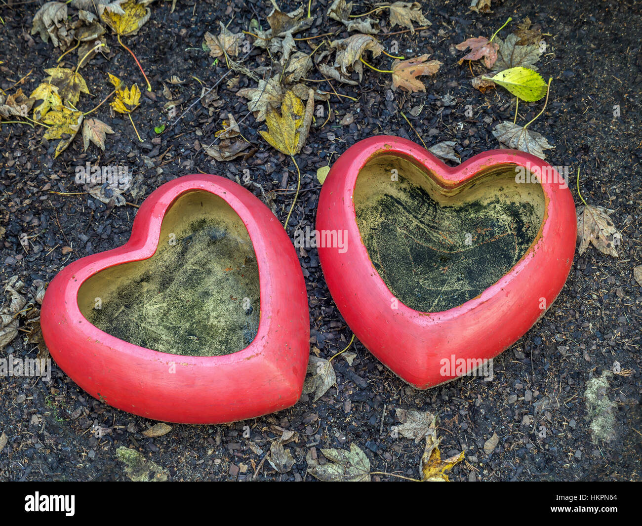 Two red heart-shaped flowerpots placed in the garden Stock Photo