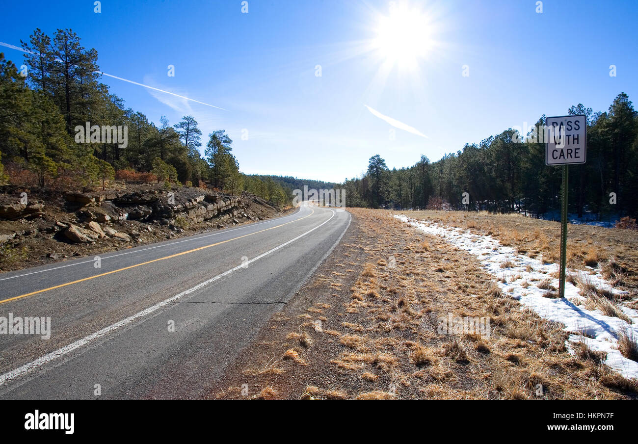 Pass with care sign on a windy forested road with snow Stock Photo Alamy