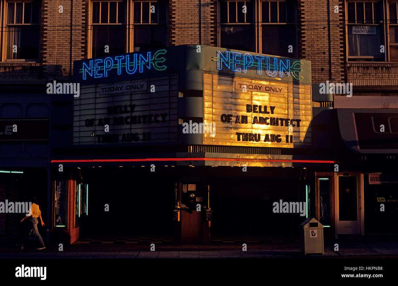 Sunset with Neptune Theater with person walking by the ticket booth in front of the theater University District Seattle Washington State USA Stock Photo