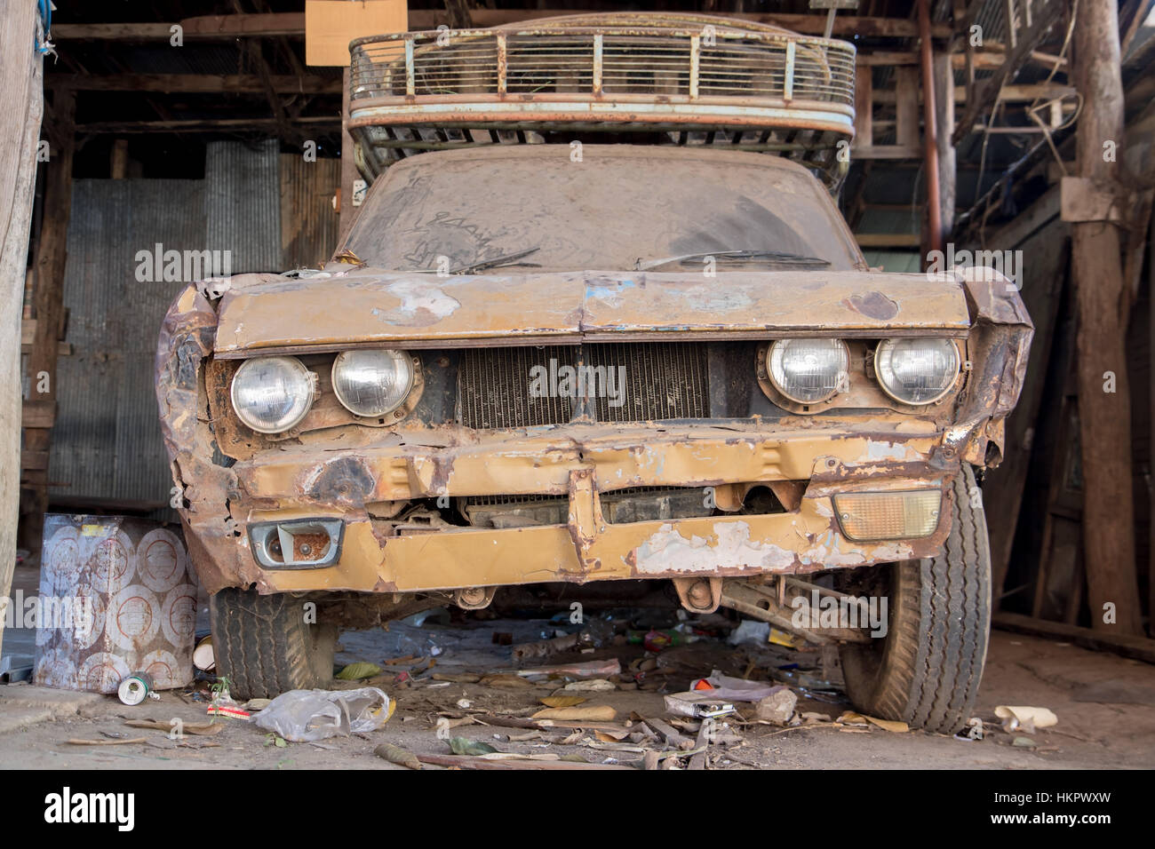 The old dusty car parked in the garage. Broken car, front view. Stock Photo