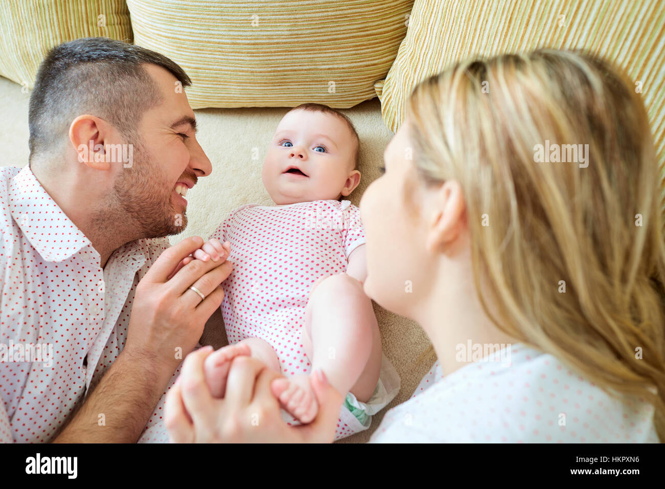 Baby with mom and dad smiling laughs in the room Stock Photo - Alamy