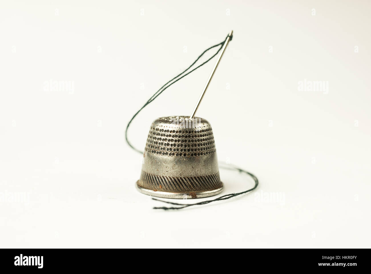 Metal thimble and needle with thread on over white Stock Photo Alamy
