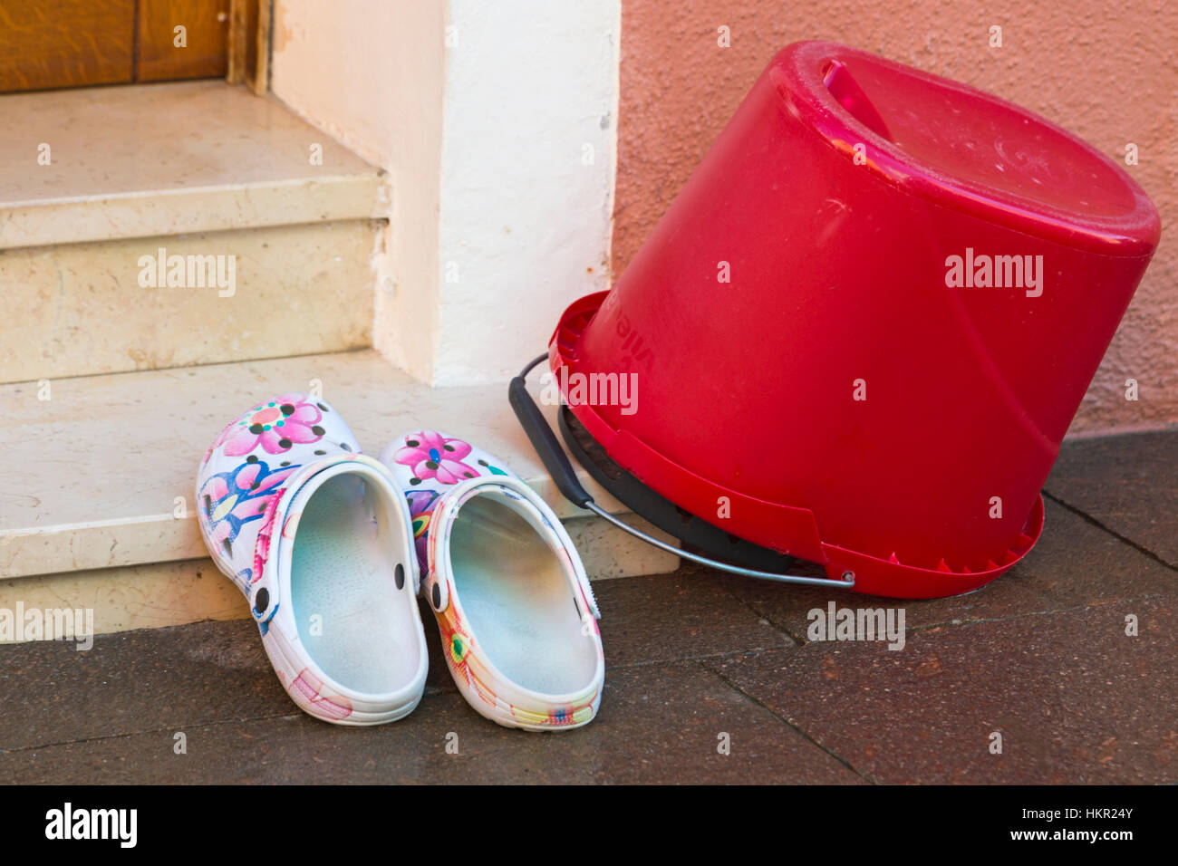 Red bucket and shoes left on steps in doorway at Burano, Venice, Italy in January Stock Photo