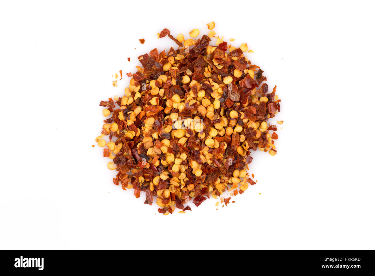 The pile of a crushed red pepper, dried chili flakes and seeds isolated on white background