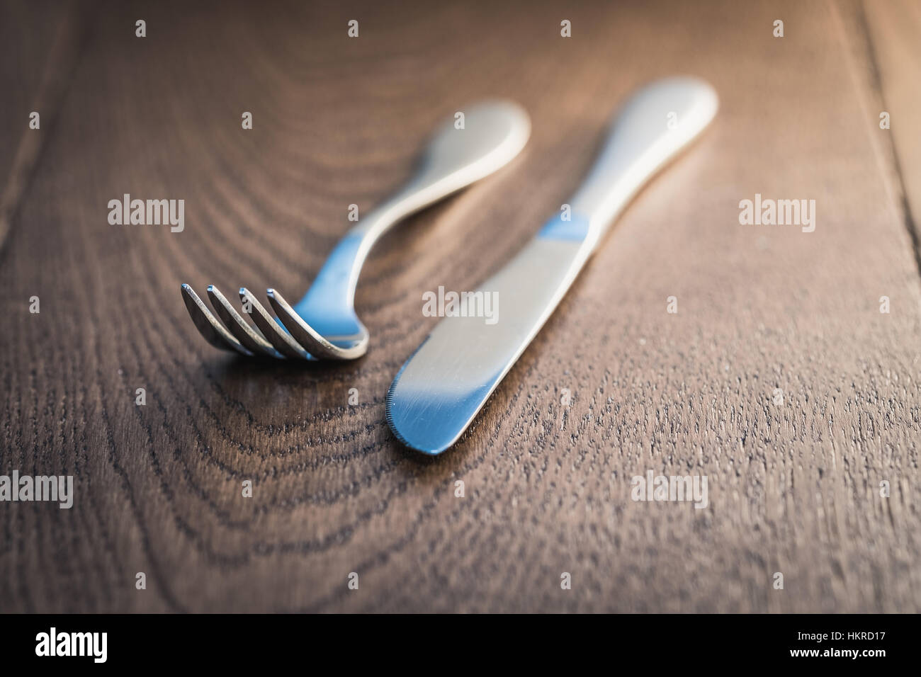 Silver knife and fork on oak table top Stock Photo - Alamy