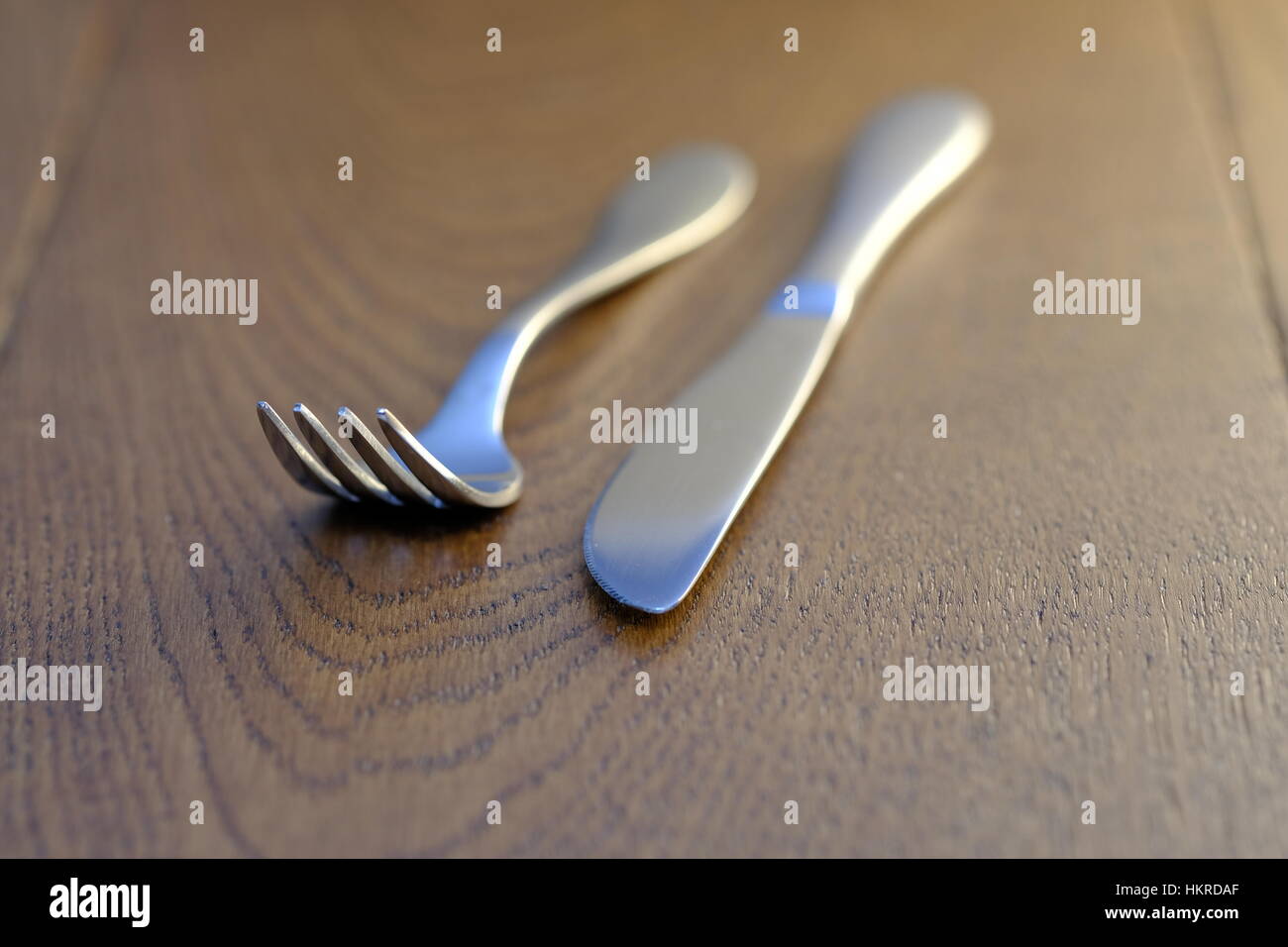 Silver knife and fork on oak table top Stock Photo - Alamy