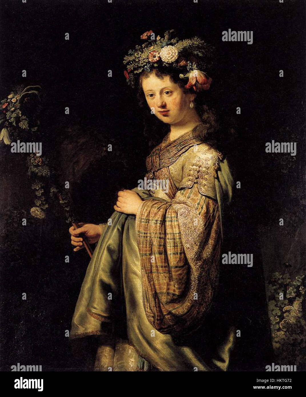 'Flora' (1634) by Rembrandt is a detailed oil painting portraying Flora, the Roman goddess of flowers and spring. The artwork captures her in a graceful pose with vibrant floral elements, demonstrating Rembrandt's mastery of light, shadow, and texture. Stock Photo
