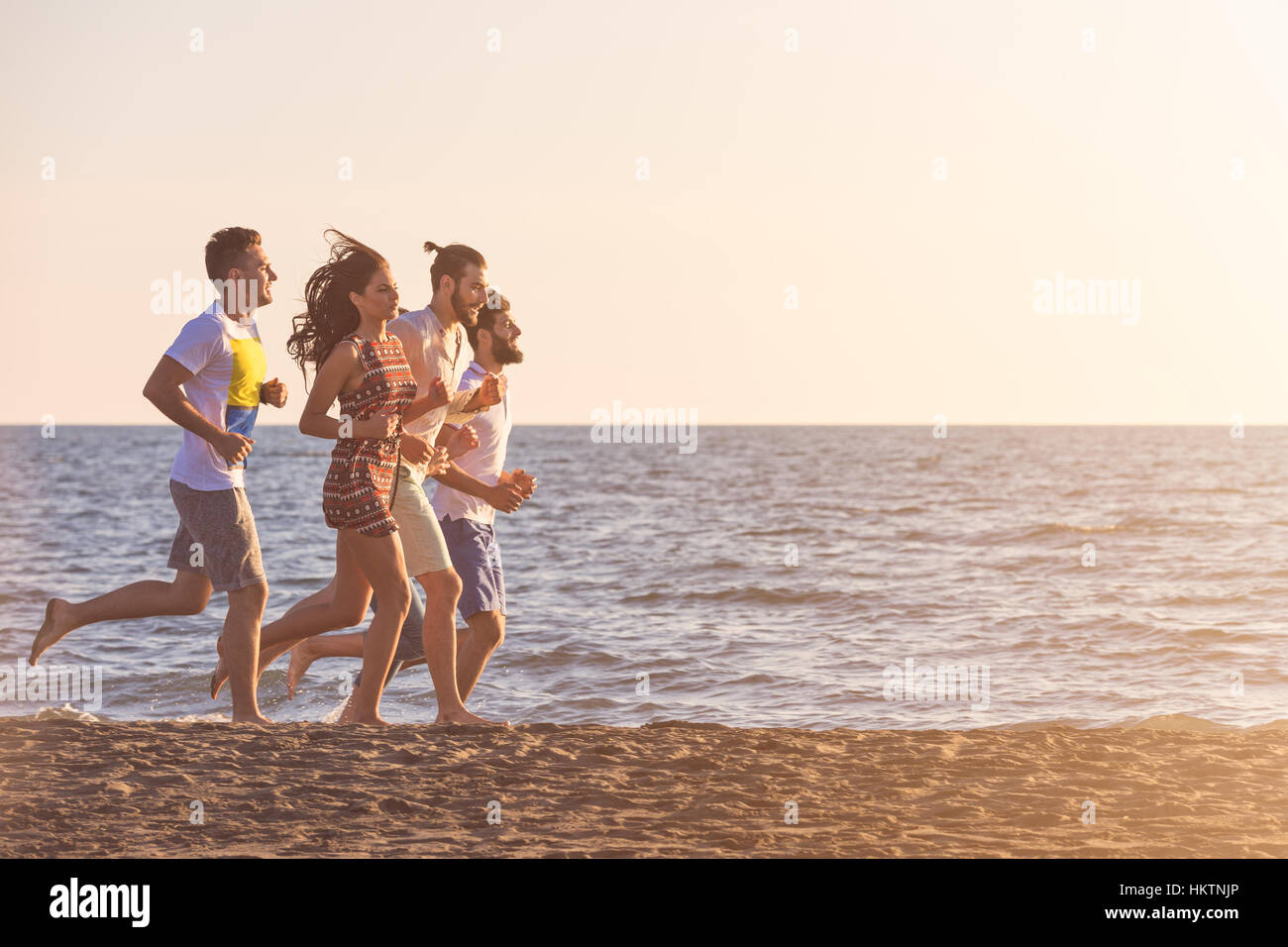 happy young people group have fun white running and jumping on beach at ...