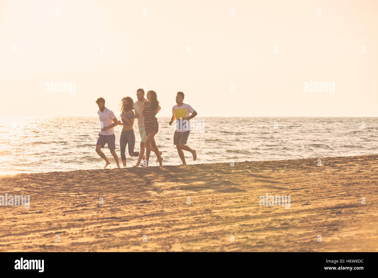 happy young people group have fun white running and jumping on beach at ...