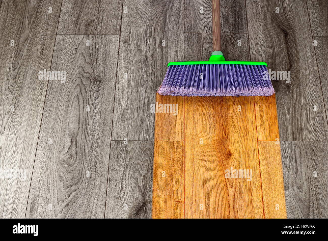 sweeping out wooden parquet with green plastic broom Stock Photo