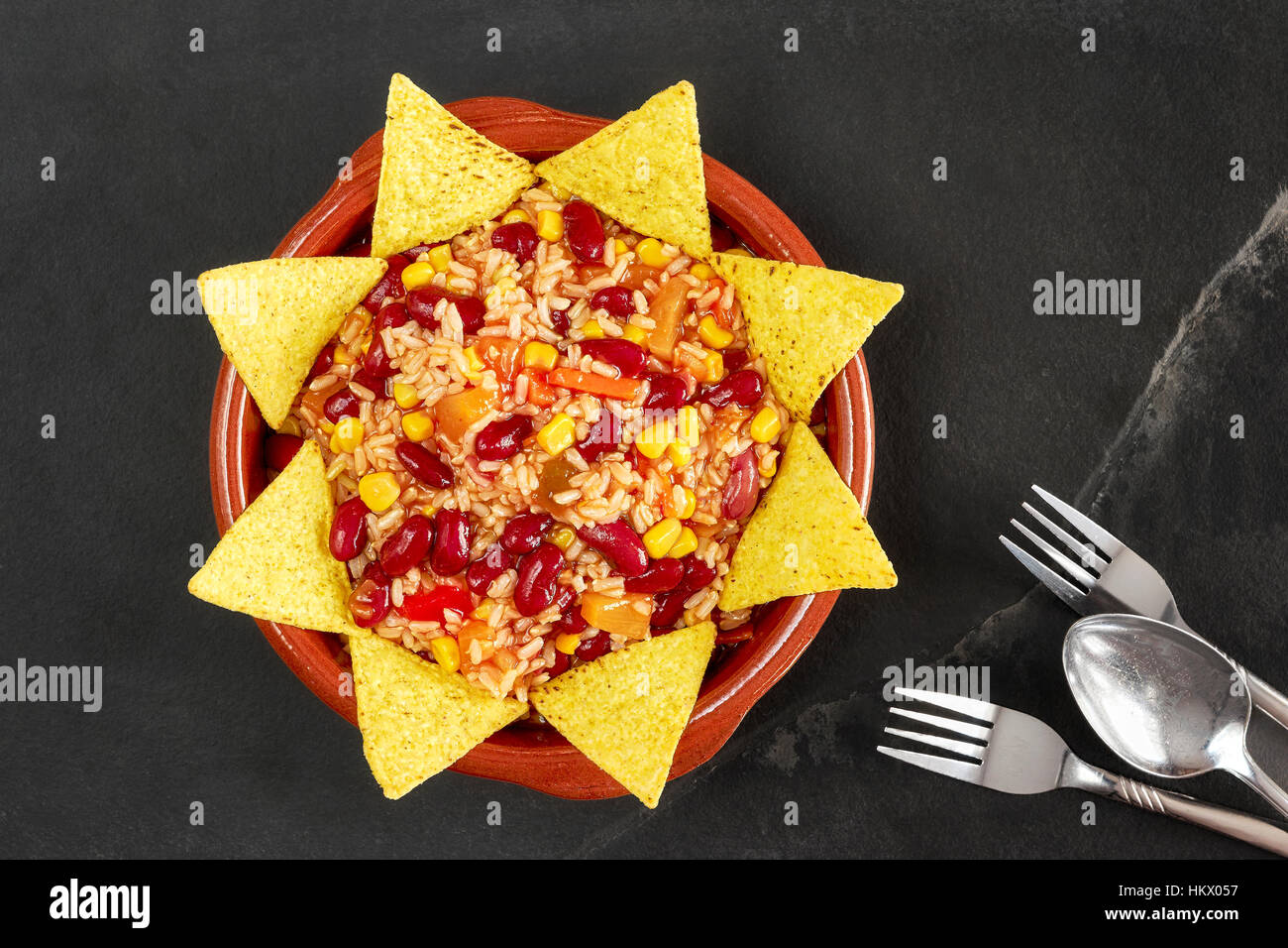 Vegetarian chili con carne in bowl with tortilla chips on slate background, top view. Stock Photo