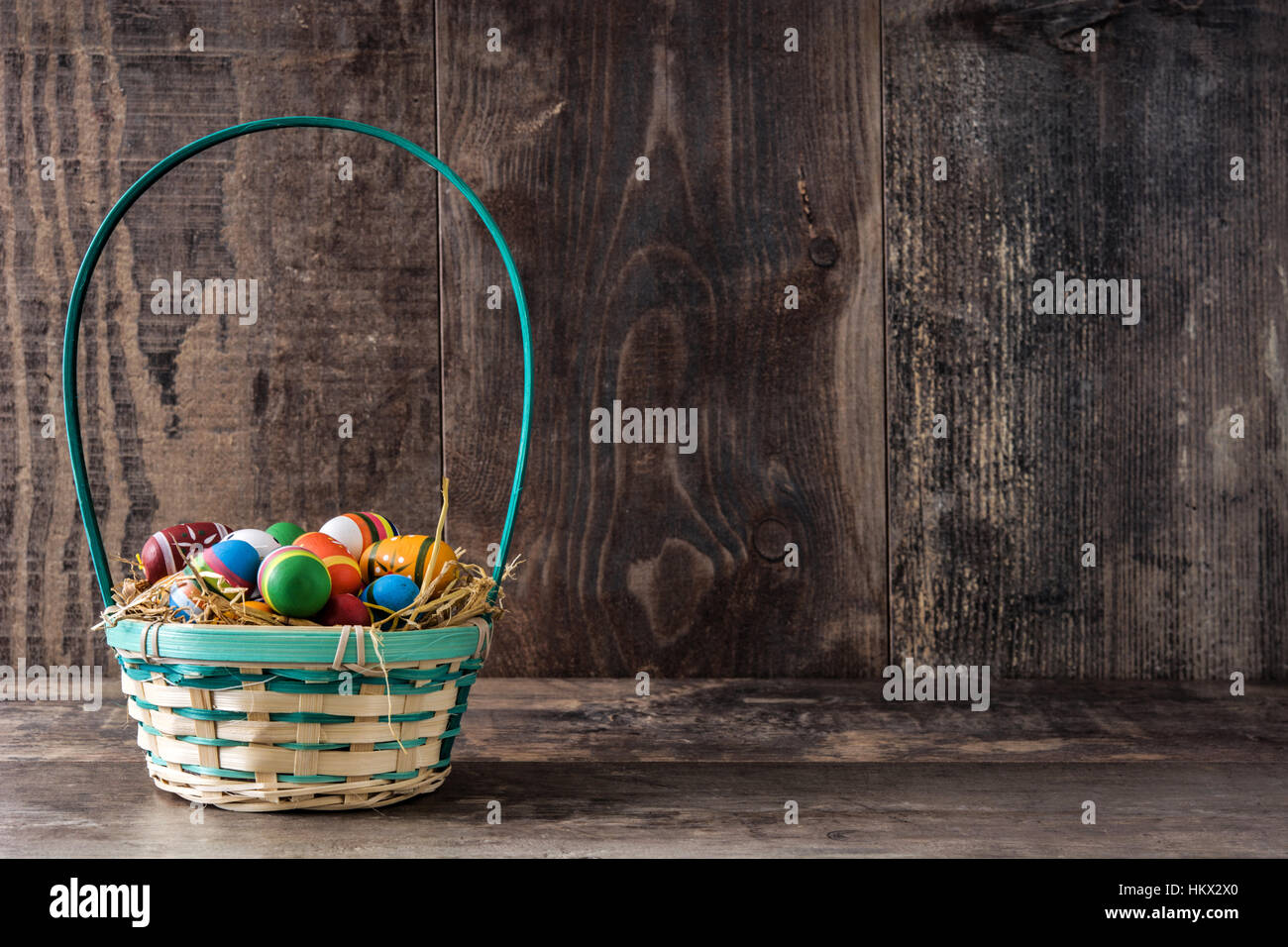 Colored easter eggs in a basket on wooden table Stock Photo - Alamy