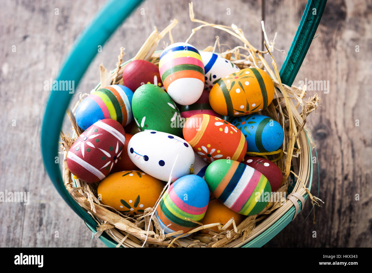 Colored easter eggs in a basket on wooden table Stock Photo - Alamy