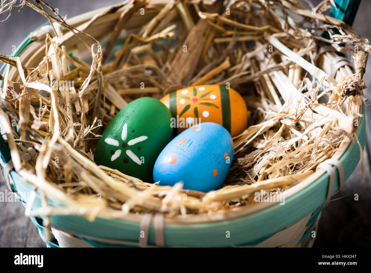 Colored easter eggs in a basket on wooden table Stock Photo - Alamy