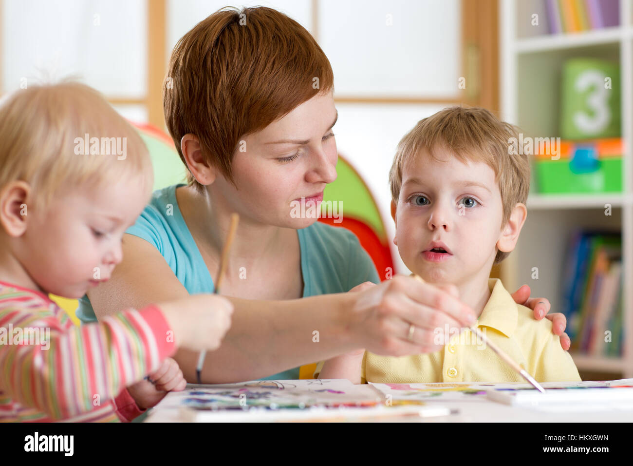Children with teacher painting in playschool Stock Photo