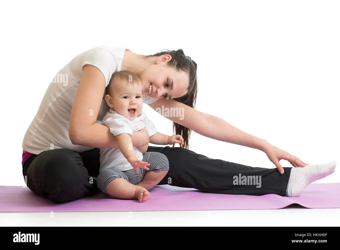 Young woman mother doing fitness exercises with baby, studio portrait isolated on white background Stock Photo