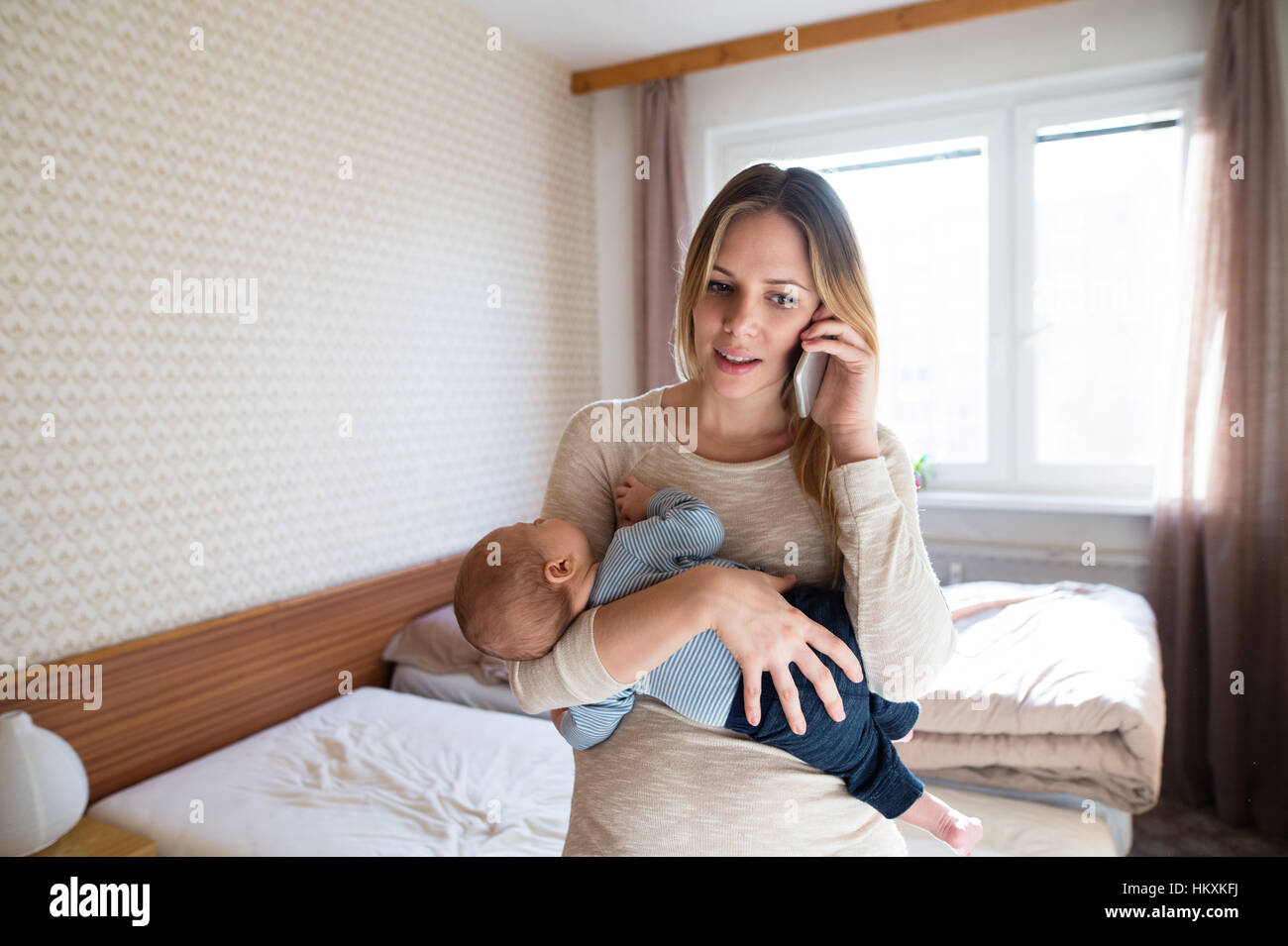 Mother holding baby son in her arms, making phone call Stock Photo - Alamy