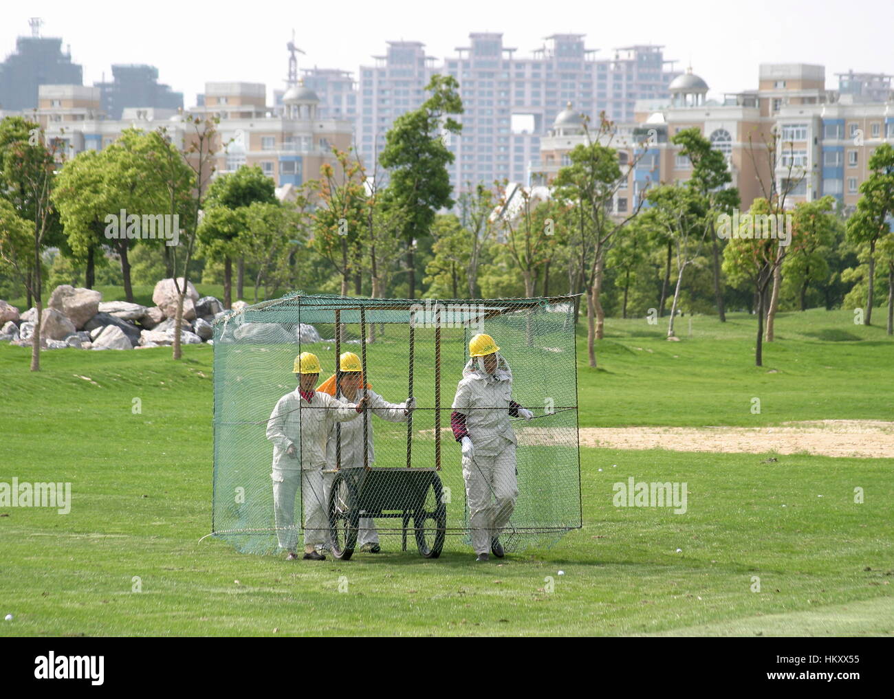 Women in a cage walk over the driving range to collect golf balls, Tomson Golf Club, BMW Asian Open 2004, Shanghai, China Stock Photo