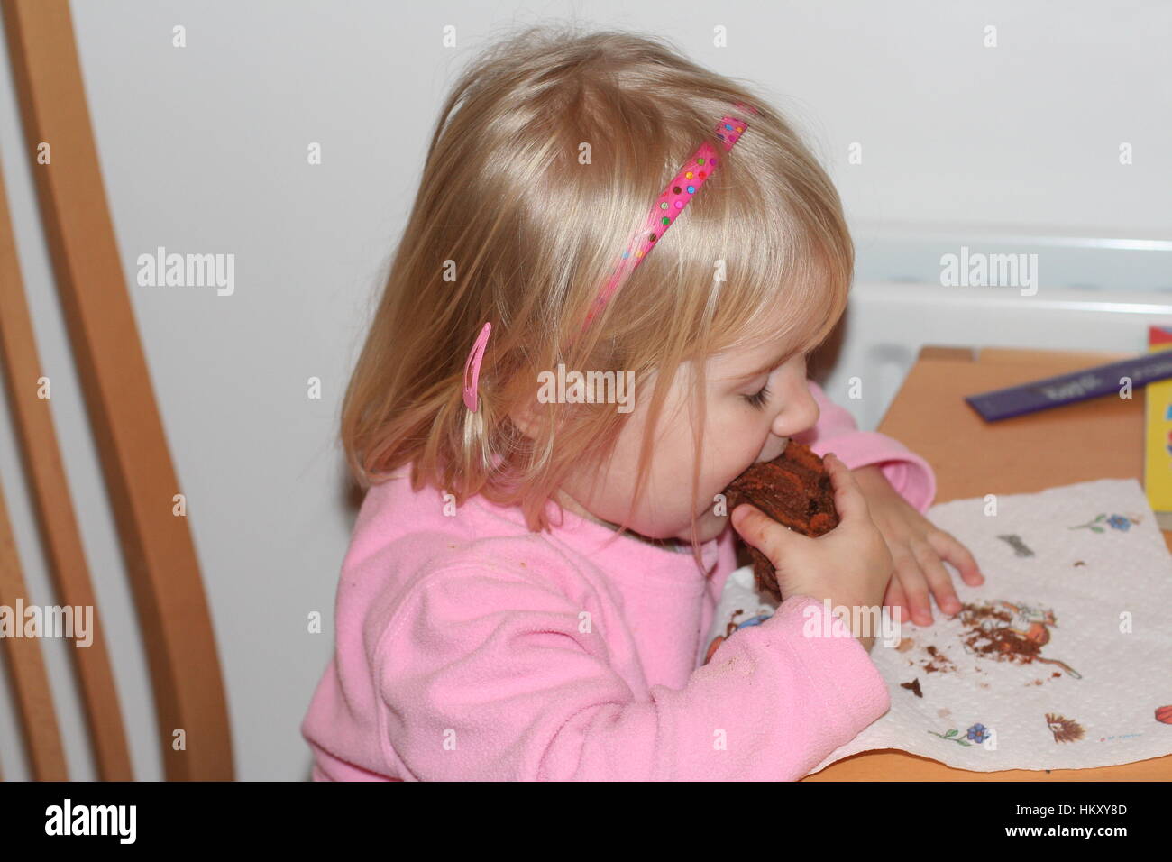 Little blonde girl/ toddler child devouring a slice of chocolate cake joy concept, happy little kid contentment concept happy happiness Stock Photo