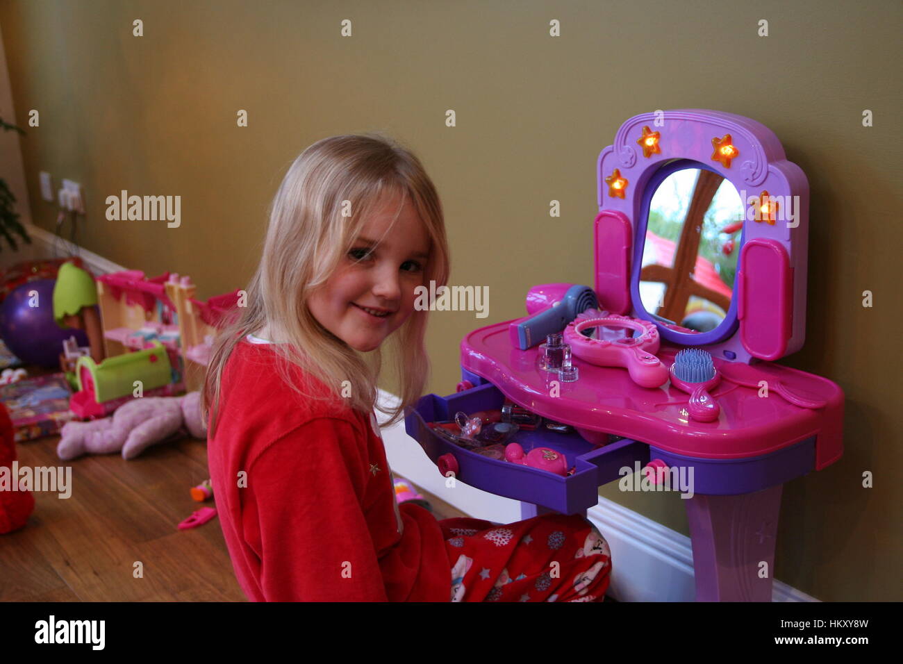 Little girl, child trying out makeup at her makeup table on christmas morning concept, presents gifts, santa came, childhood joy, excitement Stock Photo