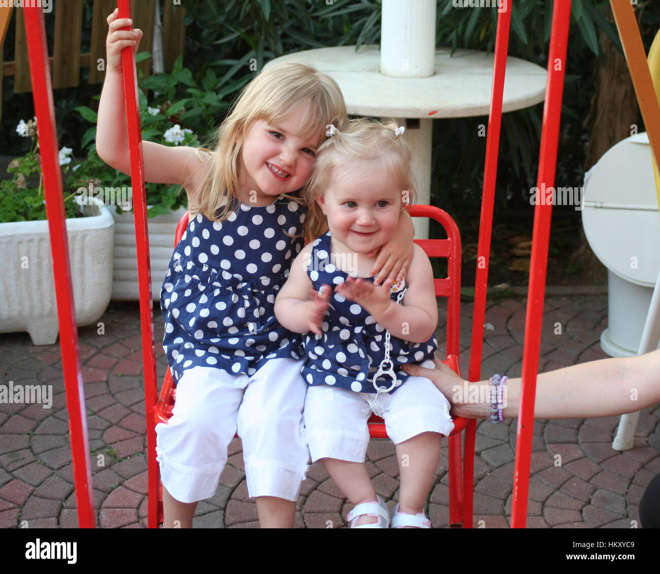 Sisters on a swing, sibling connection, sibling love, family fun, blonde little girls, childhood concept Stock Photo