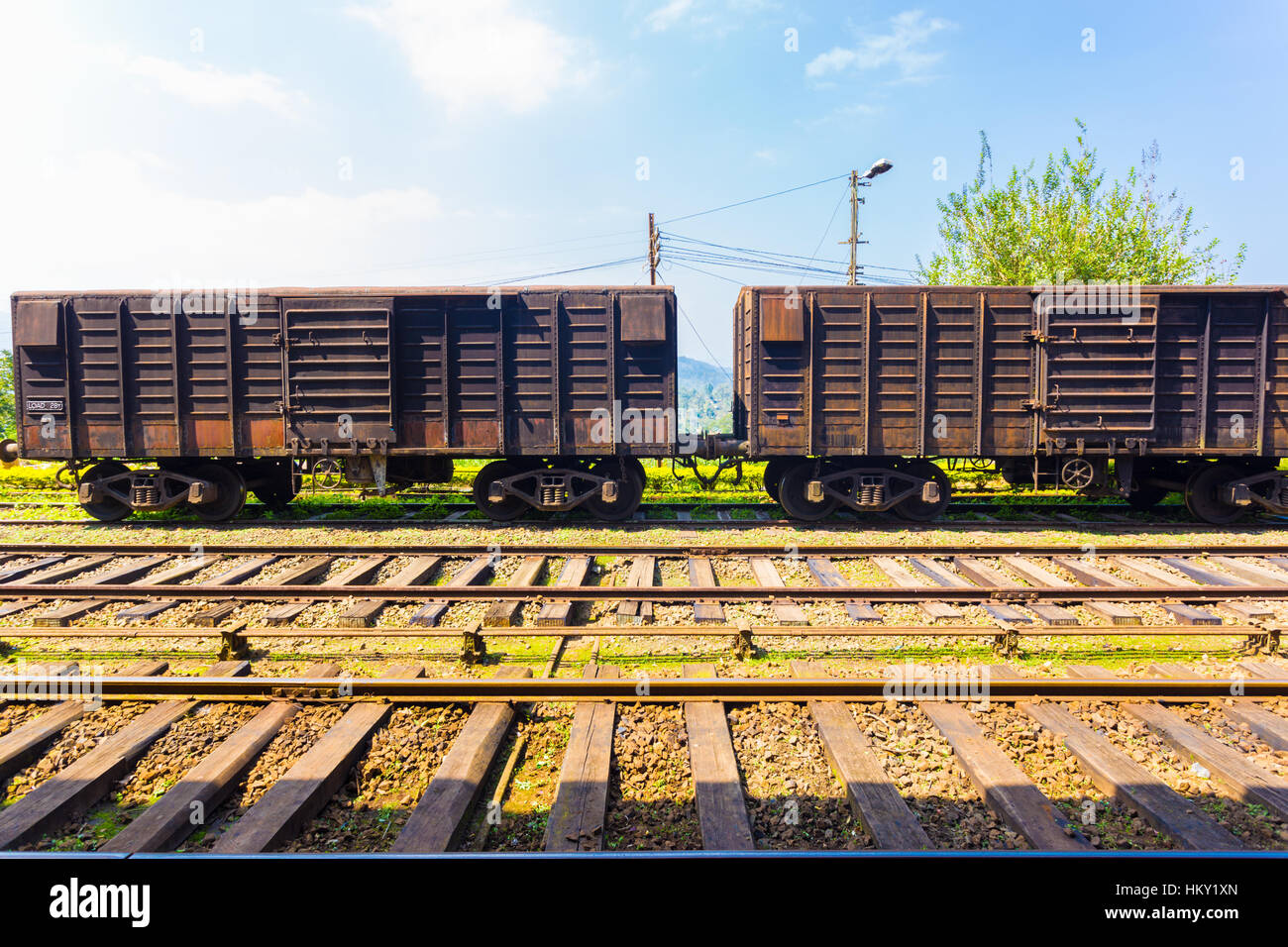 Side view of an old stationary rusted cargo carriage car sitting parked on train tracks, part of Sri Lanka Railways Stock Photo