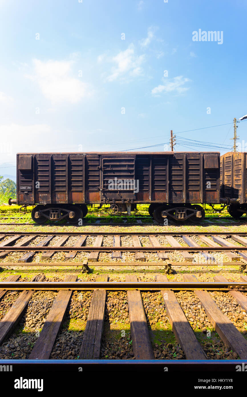 Side view of an old stationary rusted cargo carriage car sitting parked on train tracks, part of Sri Lanka Railways Stock Photo