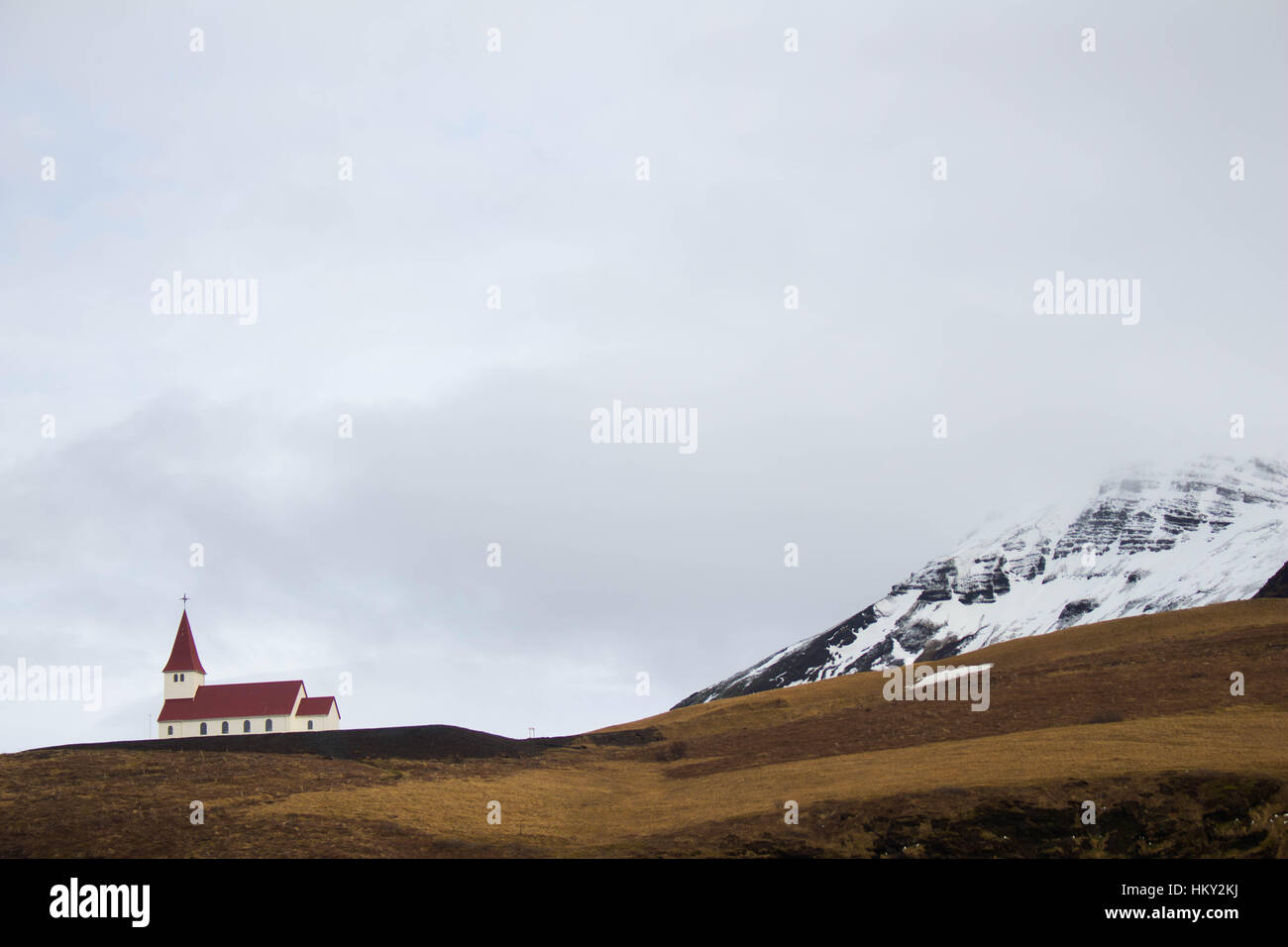 A church sits at the foot of Katla, a large active volcano in Vik, South Iceland. Stock Photo