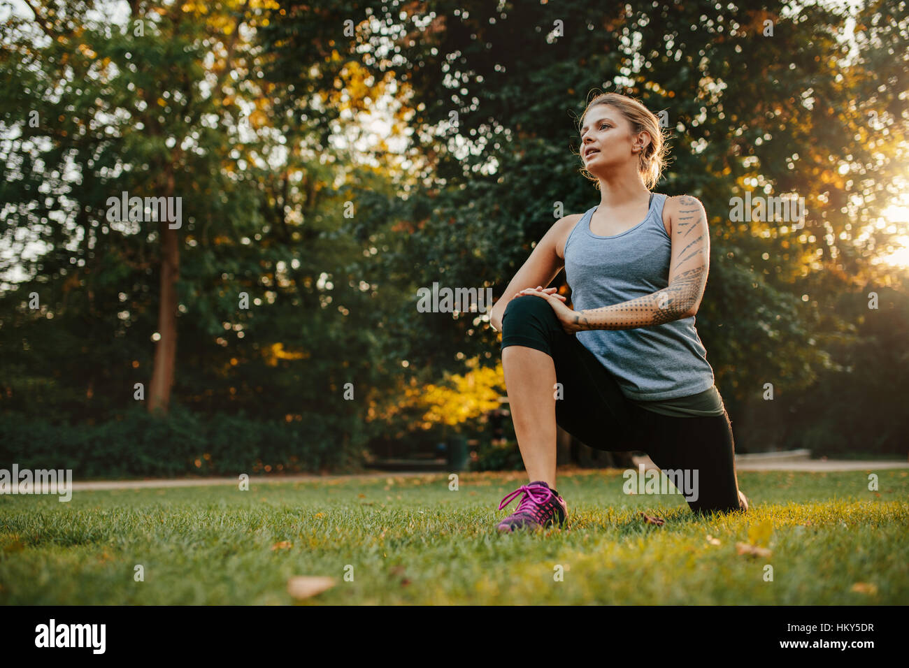 Beautiful young woman doing stretching exercise at park. Fitness model working out in morning. Stock Photo