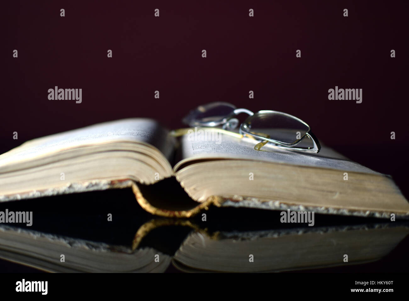 Old open book and glasses. Focus in glasses. Stock Photo