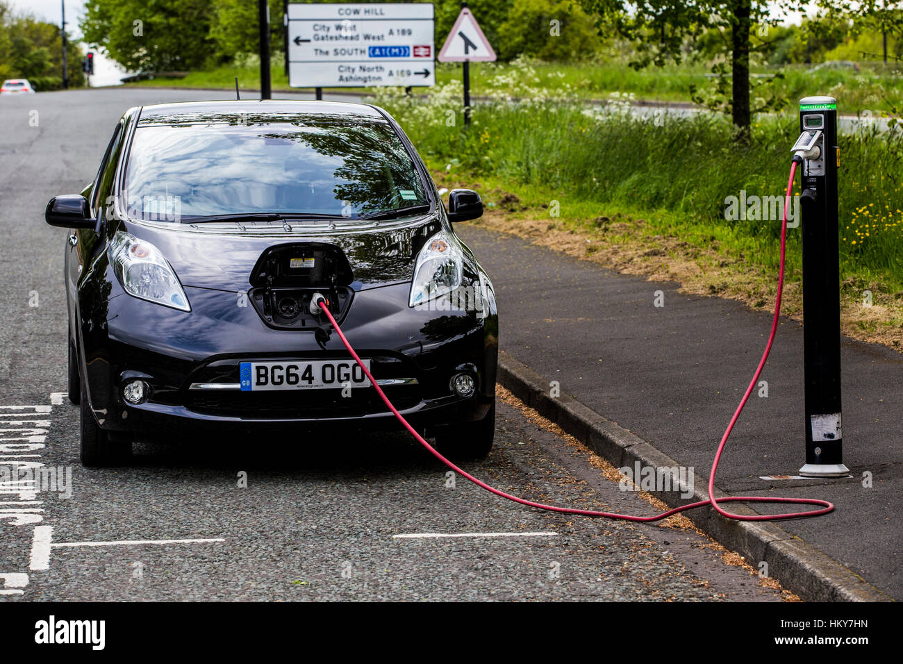 Electric Car Charging. Nissan Leaf car parked on the roadside charging from a a public charging point. Stock Photo
