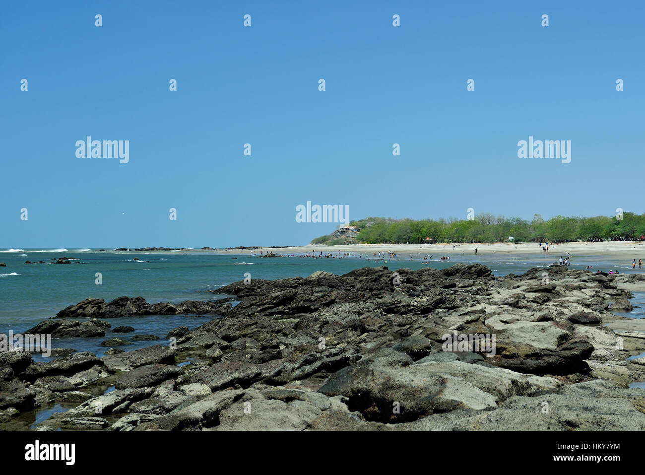 rock beach with people on sunny day with blue sky Stock Photo