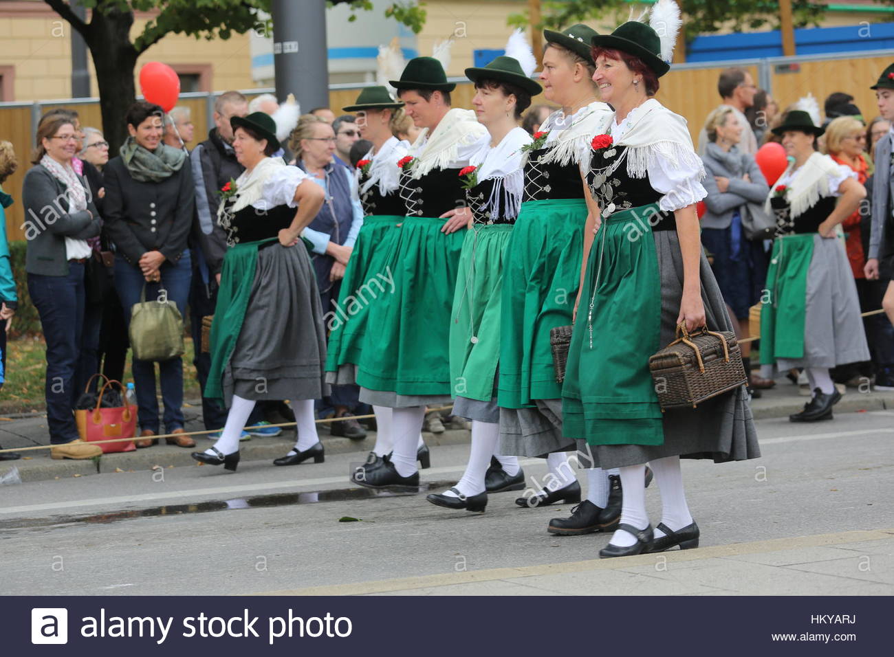 Women dressed in traditional dresses known as dirndls walk during the Oktoberfest parade. Stock Photo