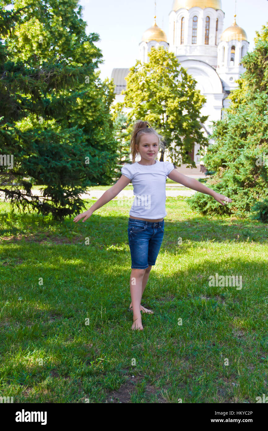 Cute girl with blond hair jumping on one leg Stock Photo