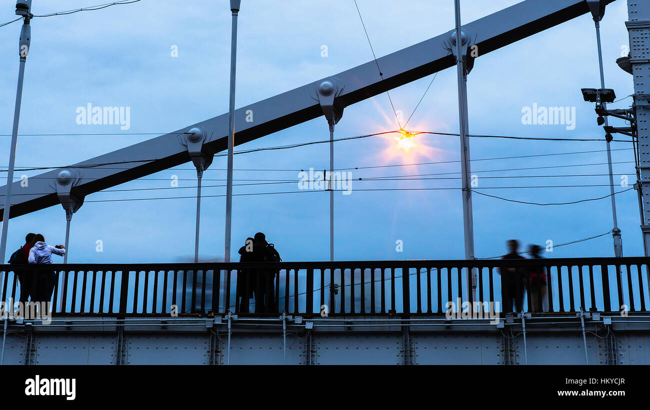 silhouettes of young people on steel bridge in dusk Stock Photo - Alamy