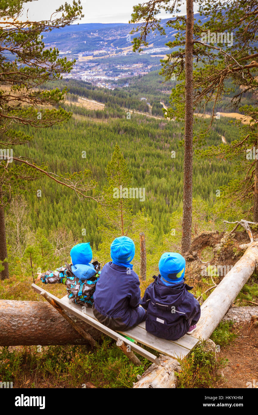 Children sitting on bench in nature, looking over landscape Stock Photo