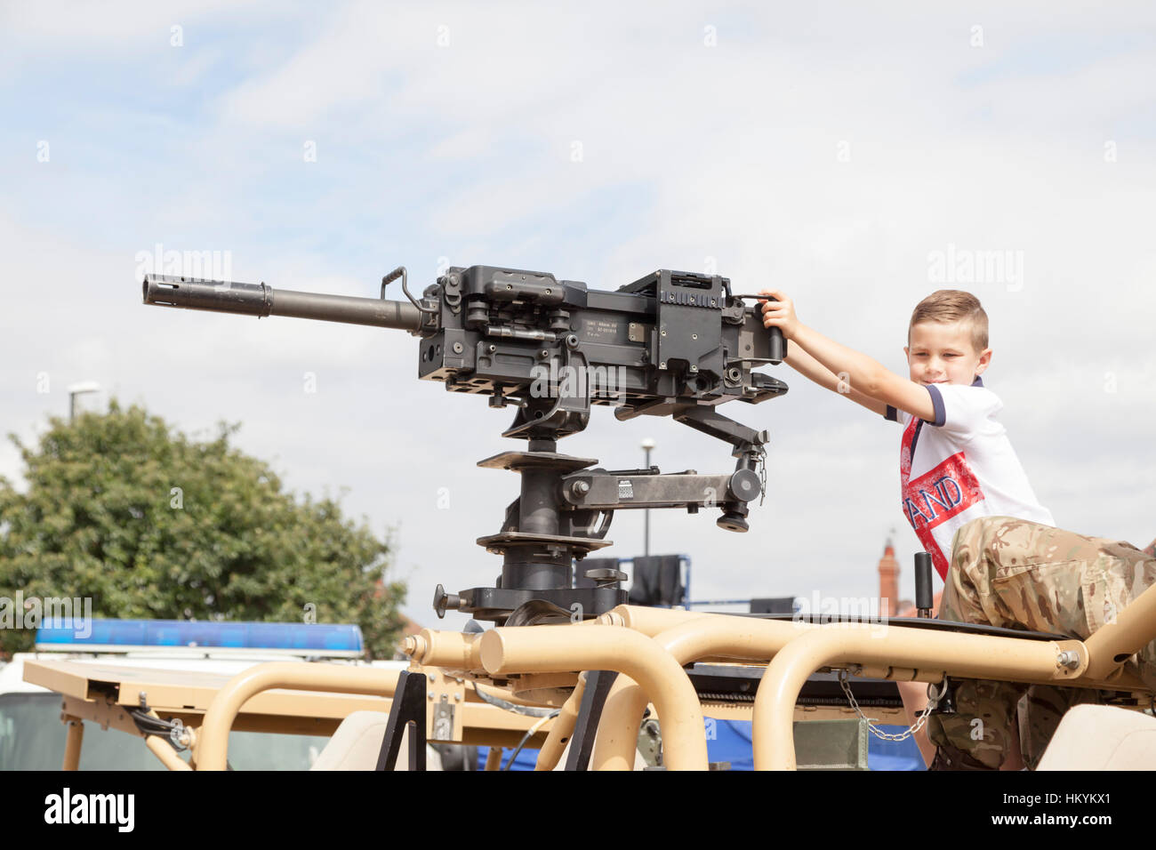 A small boy posing with a Heckler & Koch 40mm Automatic Grenade Machine Gun, on top of a British Army Land Rover Stock - Alamy