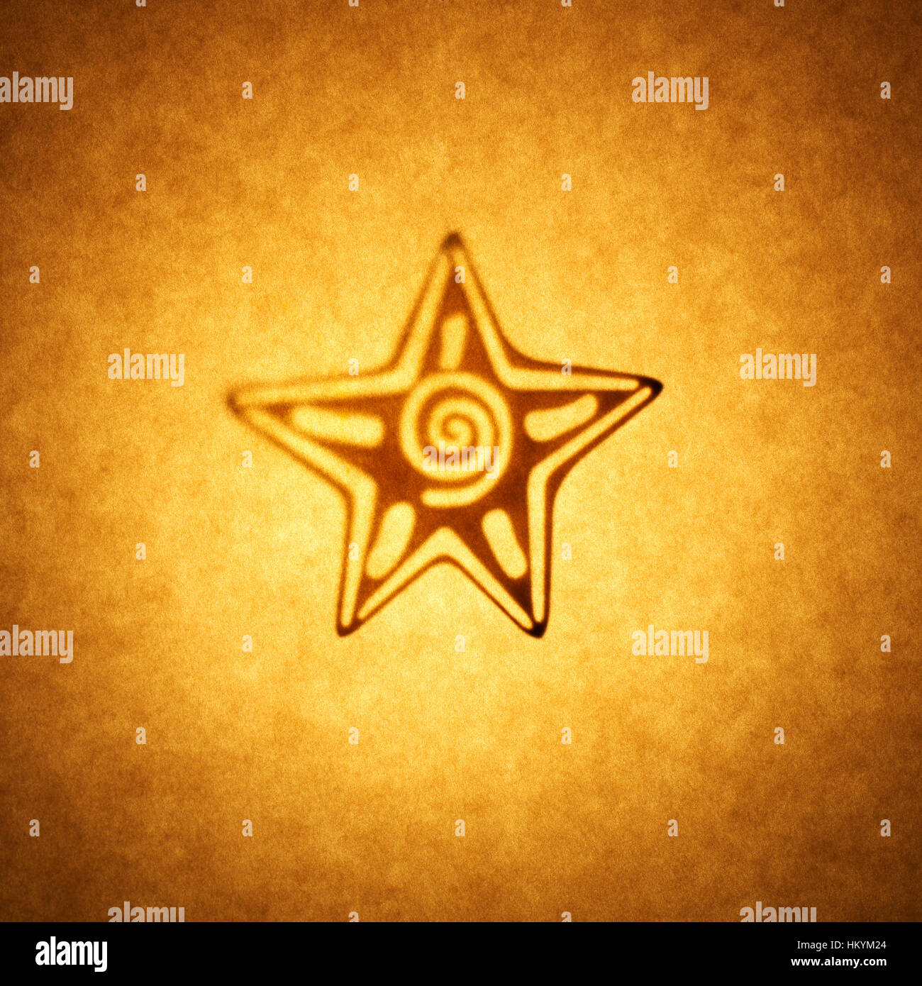 Backlit silhouette of 5 point star shape cut out against brown tone paper, with spot highlight. Stock Photo