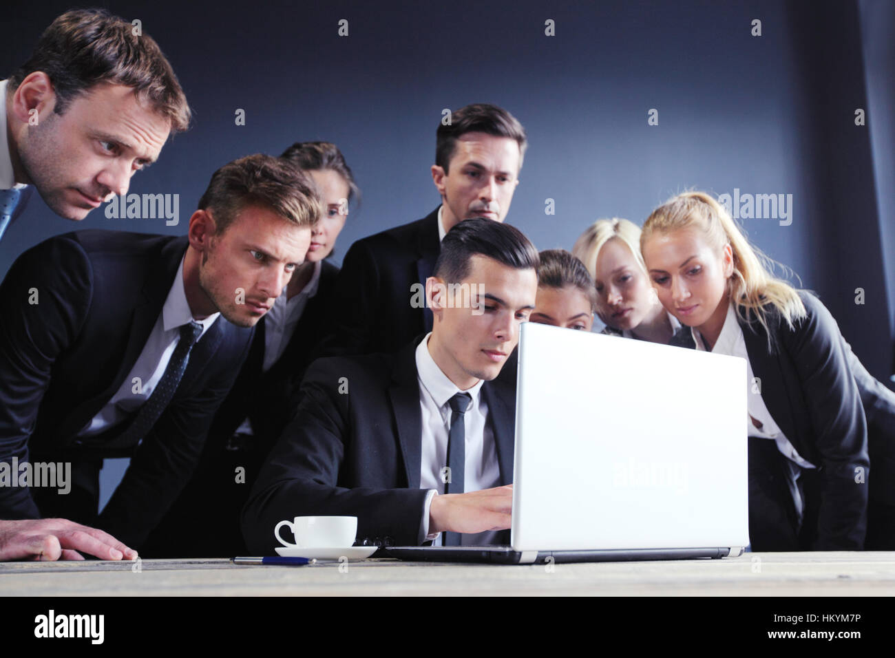 Business people gathered around laptop hi-res stock photography and ...