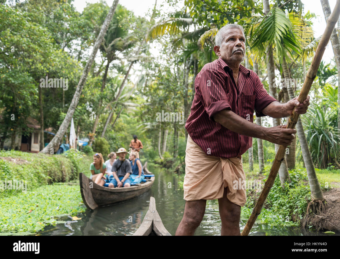 Boatman and tourist boat, Kerala Backwaters, India Stock Photo