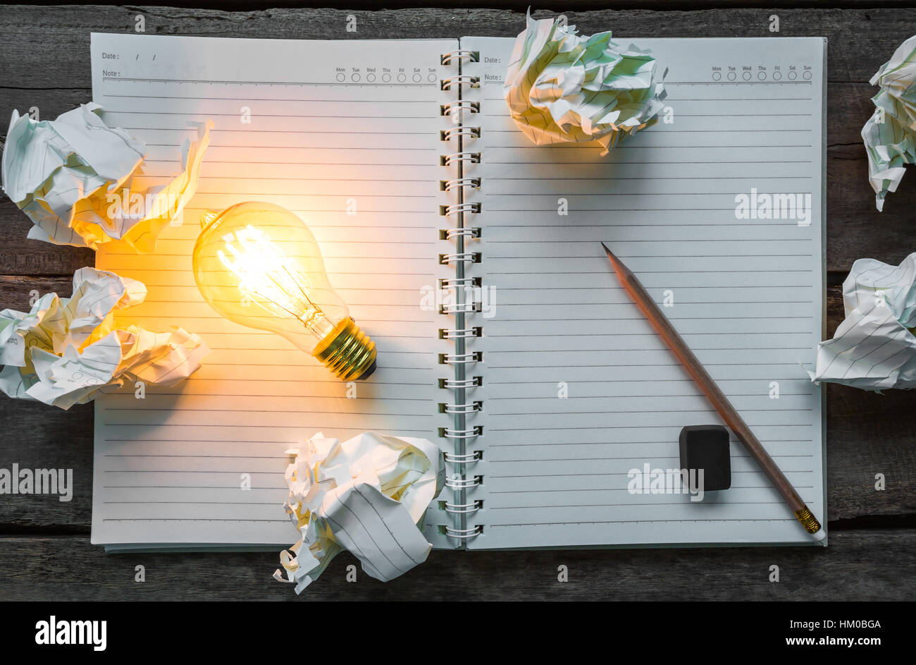 Note book and light bulb on wood table Stock Photo - Alamy
