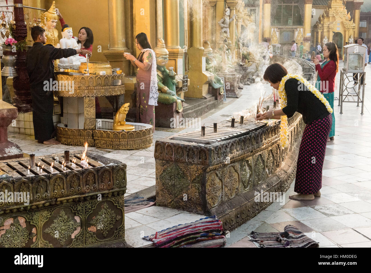Devotees of the Buddha in traditional Burmese dress pray and light