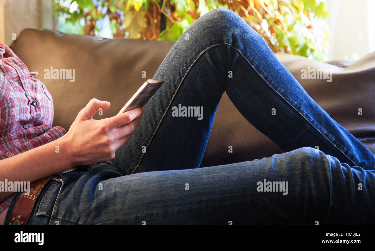 woman sitting on a sofa and holding a phone Stock Photo - Alamy
