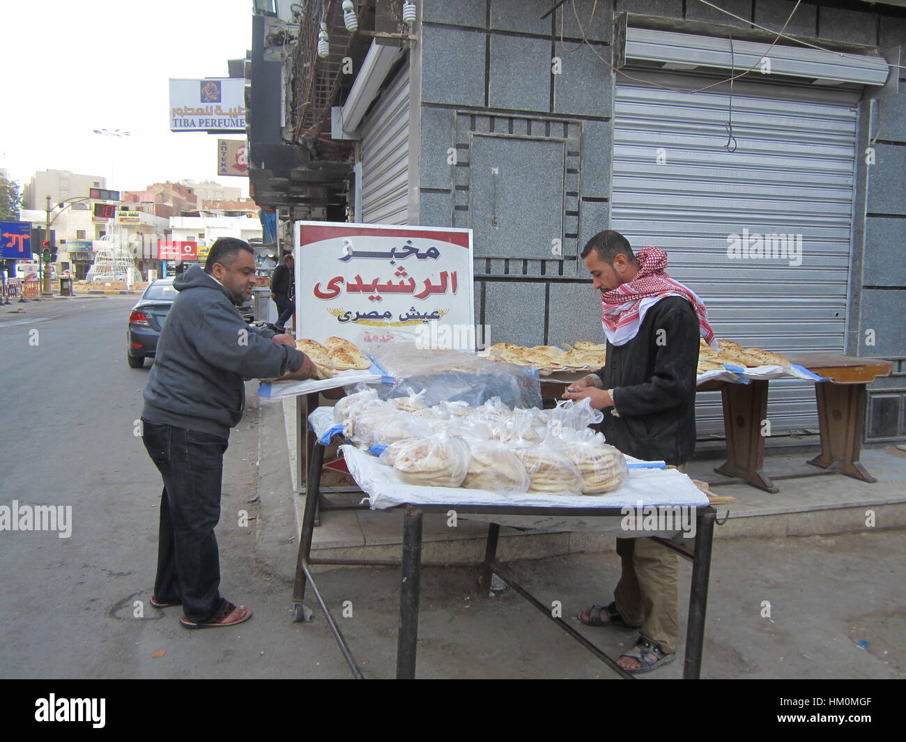 Street bread seller and a buyer at the open bread stand. Hurghada, Egypt. Stock Photo