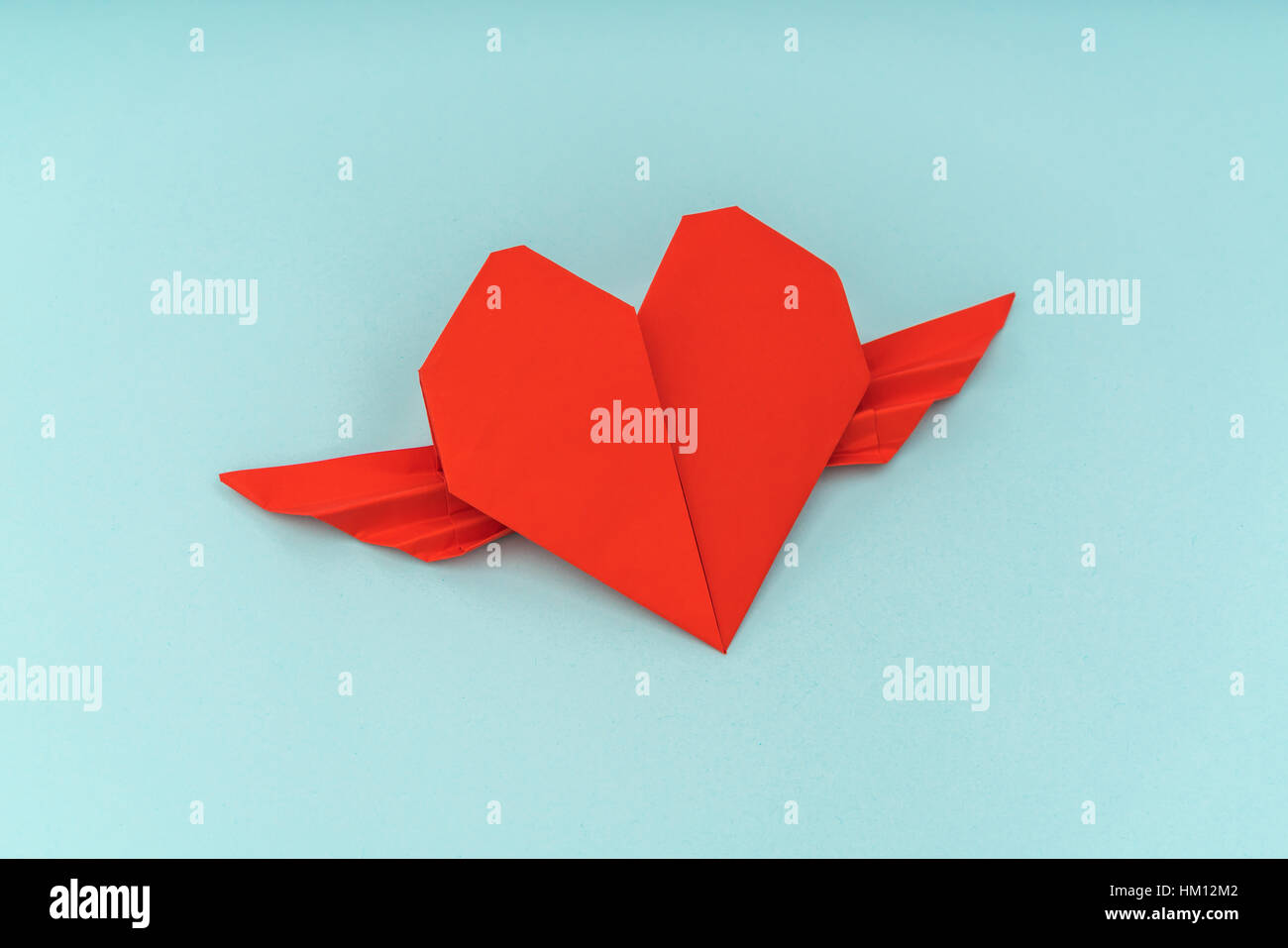Red Paper Origami Heart With Wings On Blue Background Stock
