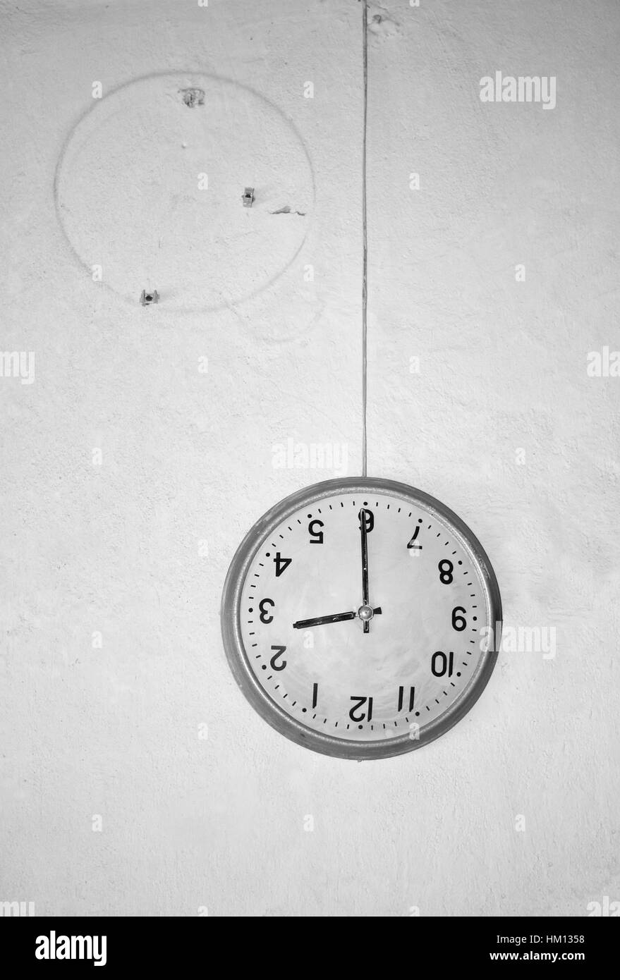 Hanging on the wire runaway wall clock. The concept of wasted time Stock Photo