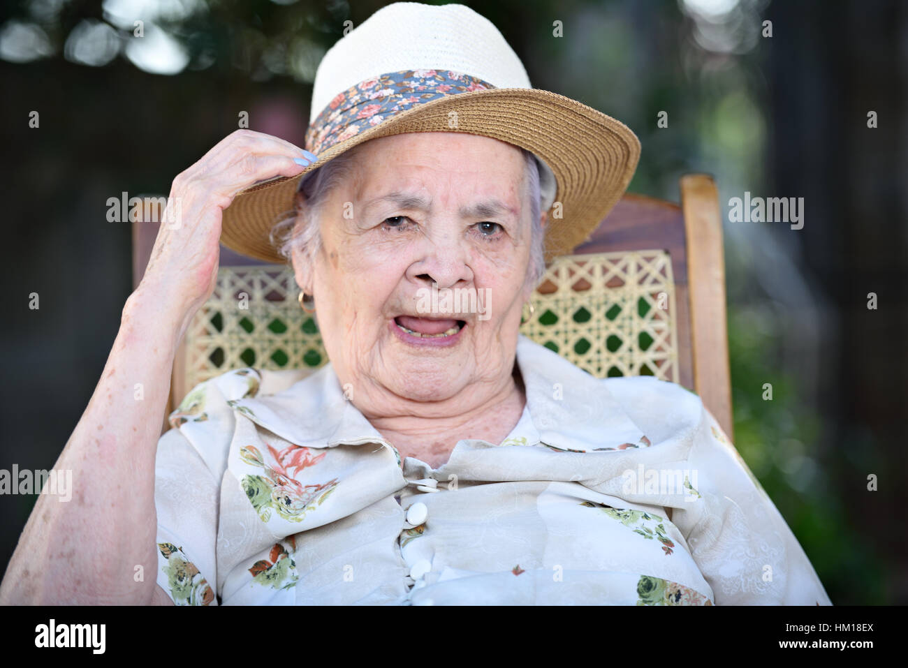 smiling grandma with hat on outside in park Stock Photo