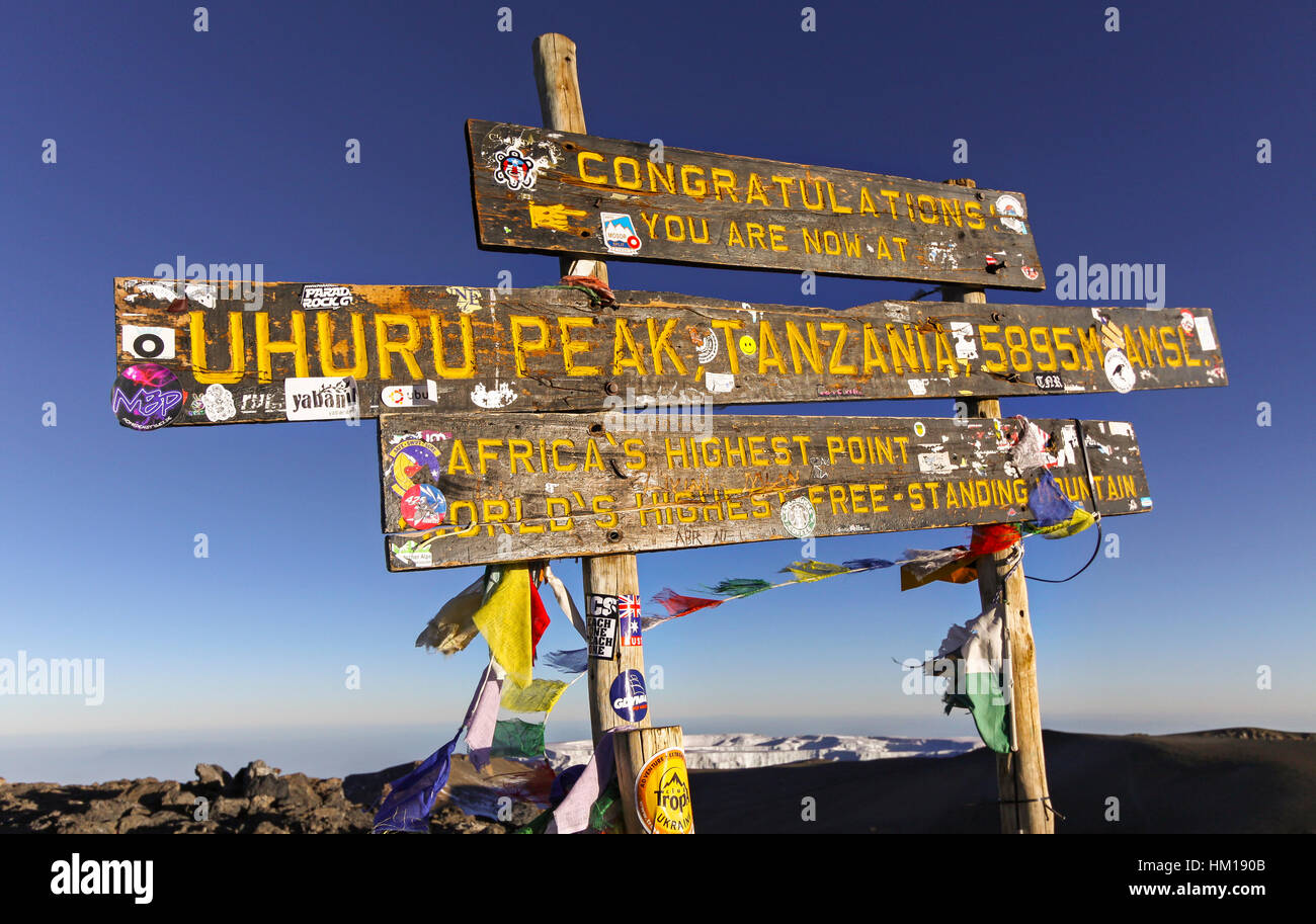 Wooden Post Table with Prayer Flags on Mount Kilimanjaro Top, Highest Africa Mountain Peak and one of Seven Summits with Iconic Glacier in Background Stock Photo